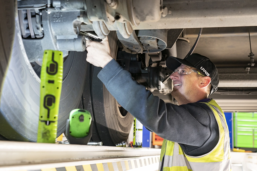 A smiling technician repairing a vehicle wheel assembly