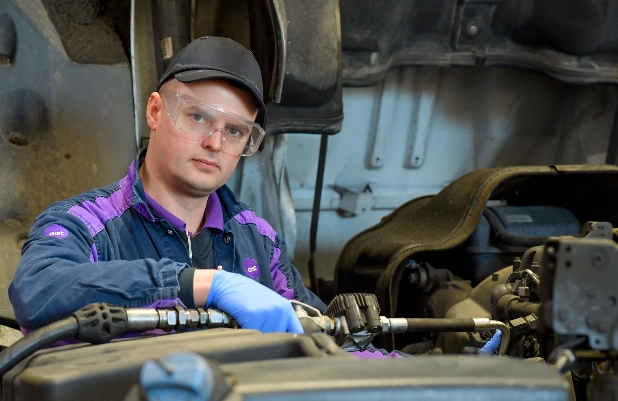 A technician wearing safety glasses working on a vehicle