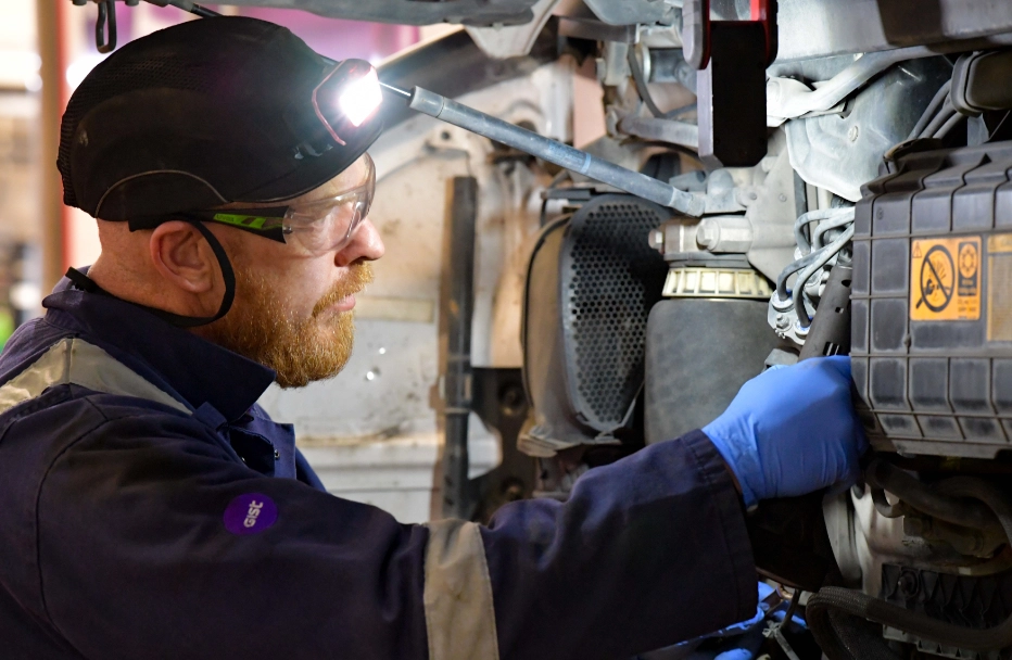 A technician using a head torch to inspect an engine