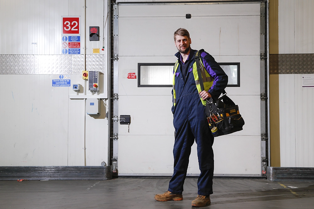 A qualified technician standing in the workshop with his tool bag